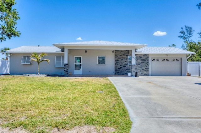 ranch-style house featuring a standing seam roof, concrete driveway, metal roof, a garage, and a front yard