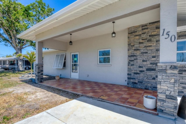 view of exterior entry featuring a patio area and stucco siding