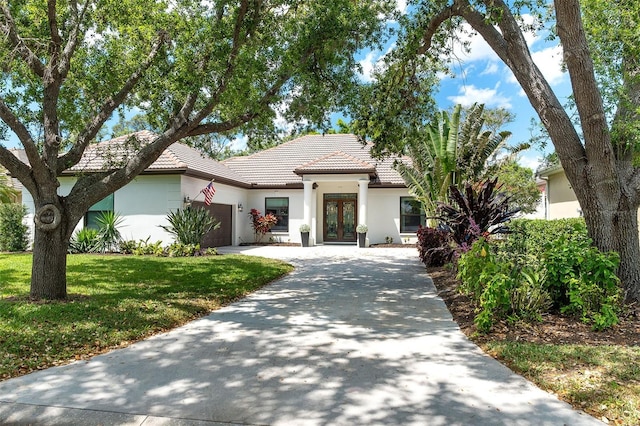 5 Saint John Blvd, Englewood, FL 34223 - view of front of property featuring french doors, stucco siding, an attached garage, a tile roof, and driveway