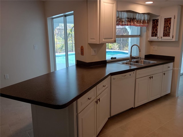 kitchen featuring dark countertops, white dishwasher, a sink, and a wealth of natural light