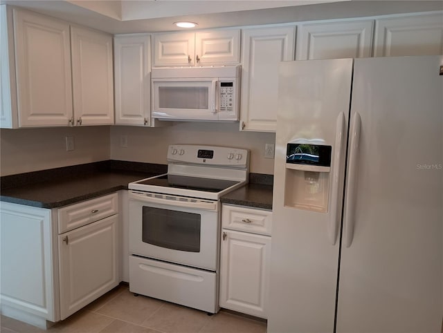 kitchen with dark countertops, white appliances, white cabinetry, and light tile patterned floors