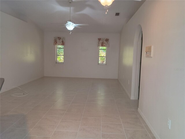 unfurnished room with arched walkways, visible vents, ceiling fan, and light tile patterned floors