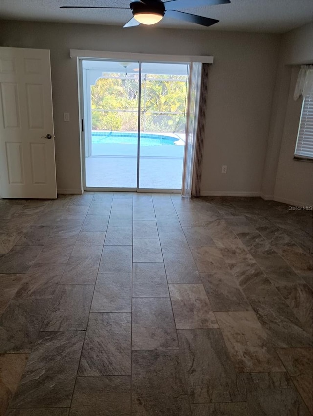 spare room with a ceiling fan and baseboards