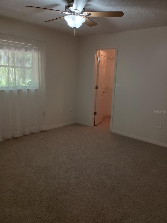 spare room with light carpet, baseboards, a textured ceiling, and ceiling fan