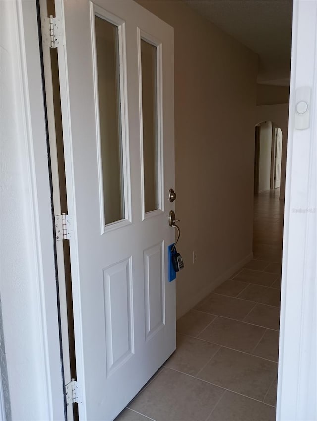 hallway with arched walkways and tile patterned flooring