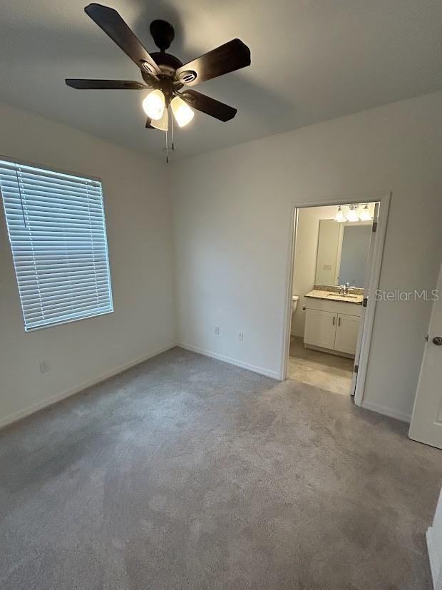 15968 Honeysuckle St, Port Charlotte, FL 33953 - unfurnished bedroom featuring a sink, light colored carpet, baseboards, connected bathroom, and ceiling fan