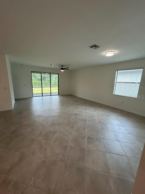 15968 Honeysuckle St, Port Charlotte, FL 33953 - empty room with plenty of natural light, light tile patterned floors, and a ceiling fan