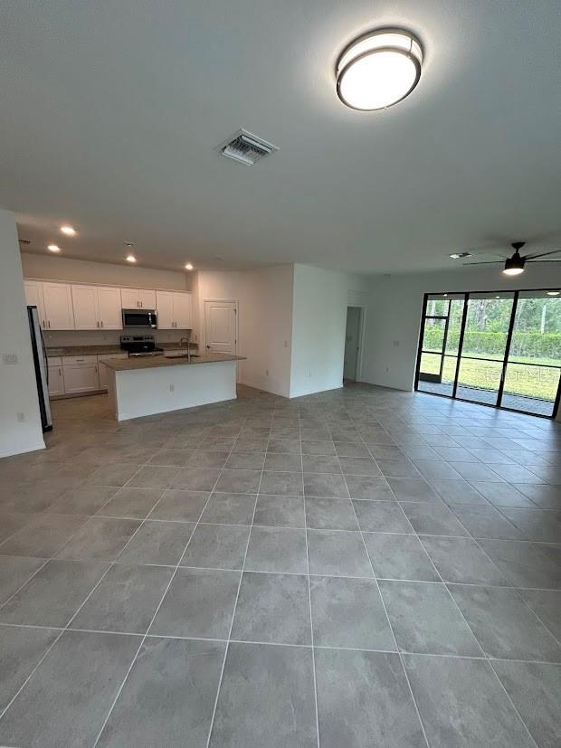 15968 Honeysuckle St, Port Charlotte, FL 33953 - unfurnished living room featuring light tile patterned floors, recessed lighting, a sink, and a ceiling fan