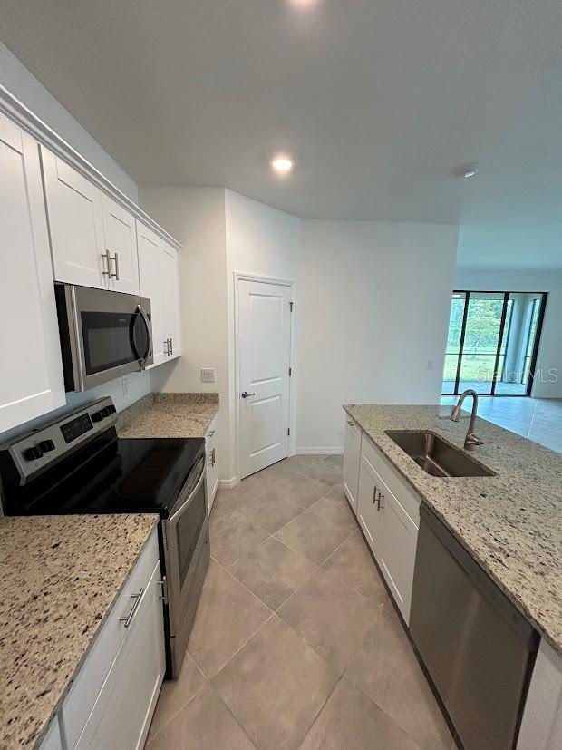 15968 Honeysuckle St, Port Charlotte, FL 33953 - kitchen with stainless steel appliances, a sink, white cabinets, light stone countertops, and recessed lighting