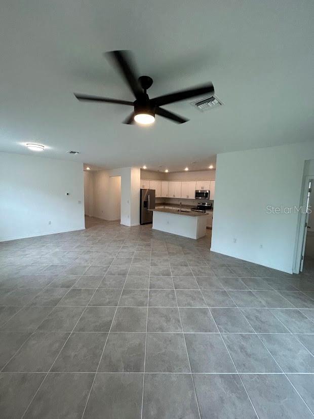 15968 Honeysuckle St, Port Charlotte, FL 33953 - unfurnished living room with ceiling fan, recessed lighting, light tile patterned floors, and a sink