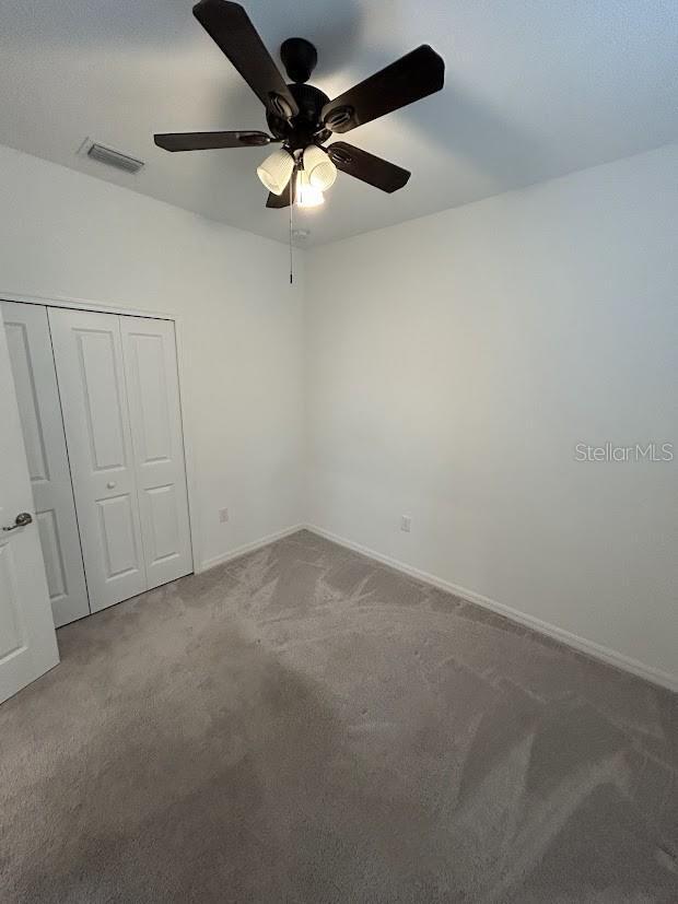 15968 Honeysuckle St, Port Charlotte, FL 33953 - unfurnished bedroom with carpet, a closet, baseboards, and ceiling fan