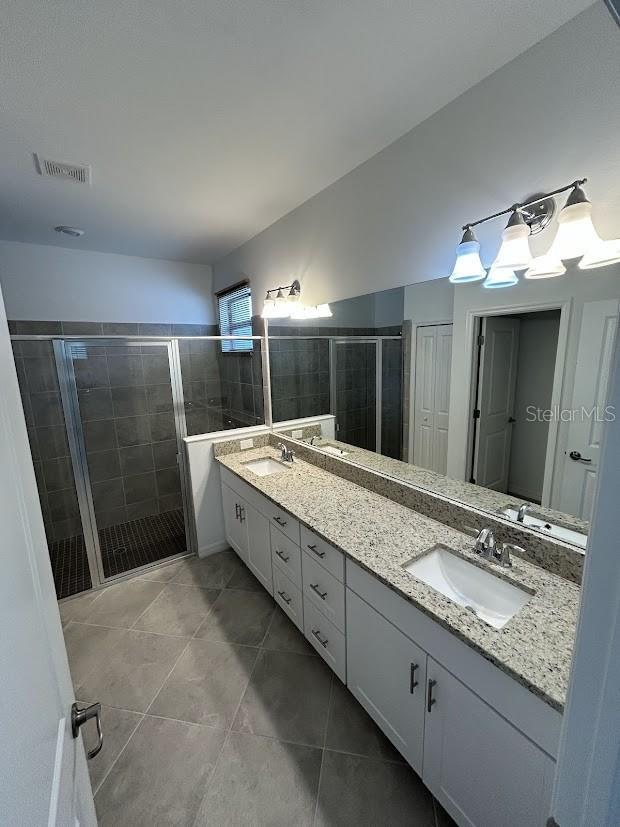15968 Honeysuckle St, Port Charlotte, FL 33953 - bathroom featuring a shower stall, tile patterned flooring, and double vanity