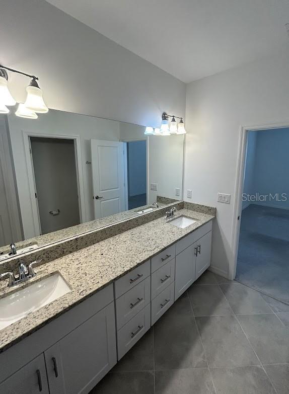 15968 Honeysuckle St, Port Charlotte, FL 33953 - bathroom with tile patterned flooring, double vanity, a chandelier, and baseboards