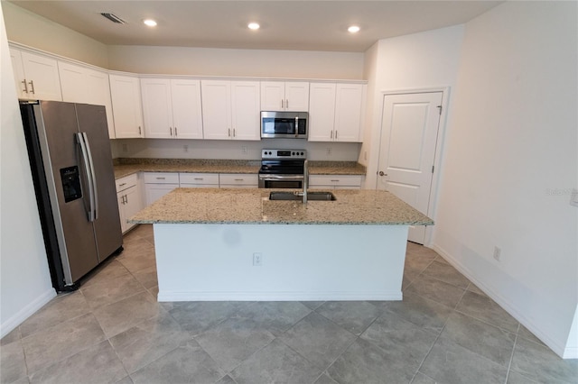 15968 Honeysuckle St, Port Charlotte, FL 33953 - kitchen with appliances with stainless steel finishes, light stone counters, white cabinets, a kitchen island with sink, and recessed lighting
