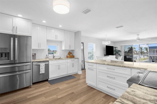 316 Coldeway Dr Unit 29, Punta Gorda, FL 33950 - kitchen featuring a wealth of natural light, white cabinets, light wood-style flooring, and stainless steel appliances