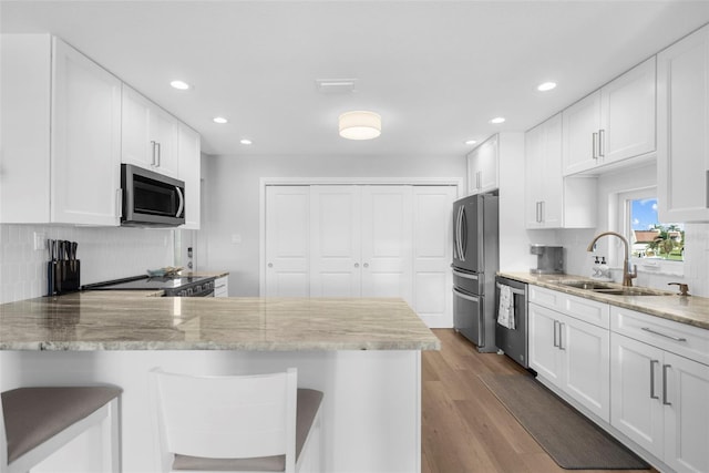316 Coldeway Dr Unit 29, Punta Gorda, FL 33950 - kitchen featuring decorative backsplash, wood finished floors, stainless steel appliances, white cabinetry, and a sink