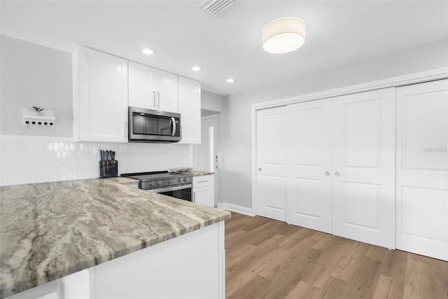 316 Coldeway Dr Unit 29, Punta Gorda, FL 33950 - kitchen with white cabinets, visible vents, light wood finished floors, stainless steel appliances, and light stone counters