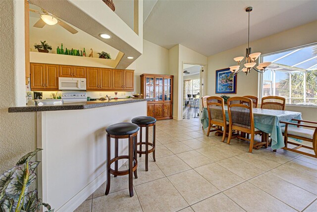 1078 Boundary Blvd, Rotonda West, FL 33947 - kitchen featuring white microwave, range with electric stovetop, brown cabinets, a kitchen breakfast bar, and high vaulted ceiling