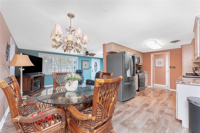 1670 Faust Dr, Englewood, FL 34224 - dining space with baseboards, light wood-type flooring, a textured ceiling, visible vents, and ceiling fan with notable chandelier