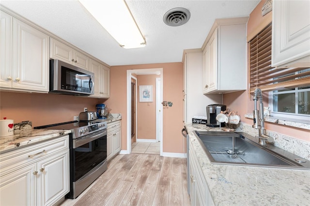 1670 Faust Dr, Englewood, FL 34224 - kitchen with light wood-style flooring, visible vents, appliances with stainless steel finishes, a sink, and baseboards