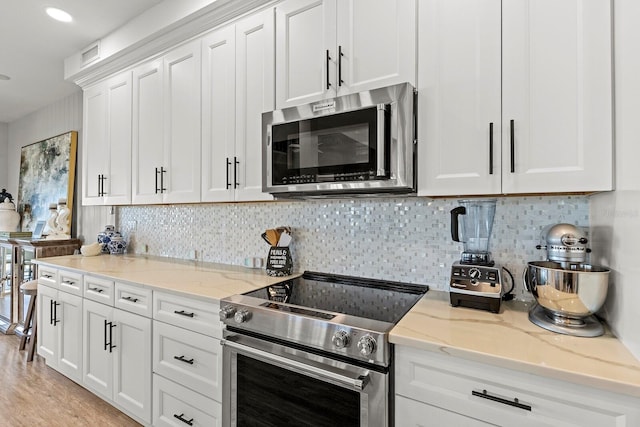 17 Seawatch Dr, Boca Grande, FL 33921 - kitchen featuring stainless steel appliances, light wood finished floors, white cabinets, backsplash, and light stone countertops