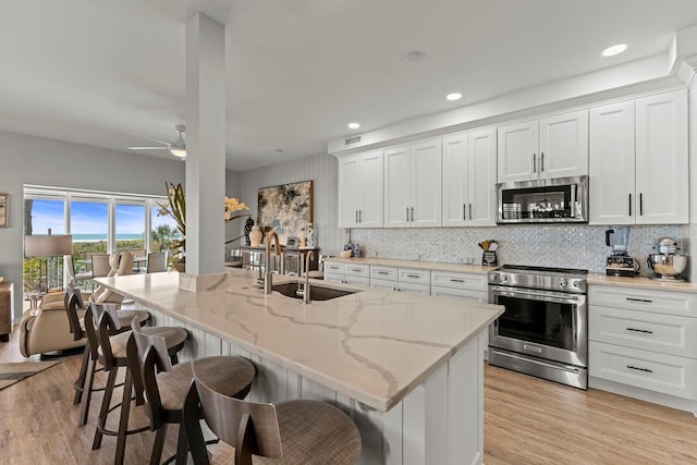 17 Seawatch Dr, Boca Grande, FL 33921 - kitchen featuring a ceiling fan, a sink, stainless steel appliances, light wood-style flooring, and white cabinets