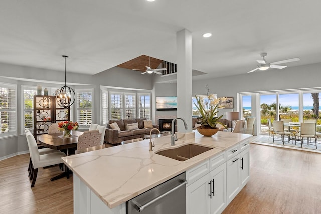 17 Seawatch Dr, Boca Grande, FL 33921 - kitchen with a warm lit fireplace, stainless steel dishwasher, a sink, open floor plan, and ceiling fan with notable chandelier