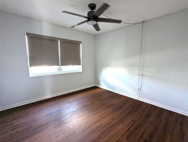 spare room featuring a ceiling fan, baseboards, and dark wood finished floors