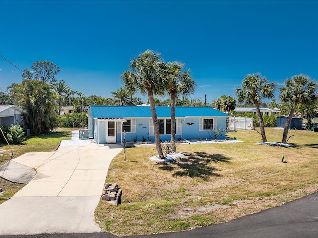 ranch-style house with fence, driveway, metal roof, and a front yard