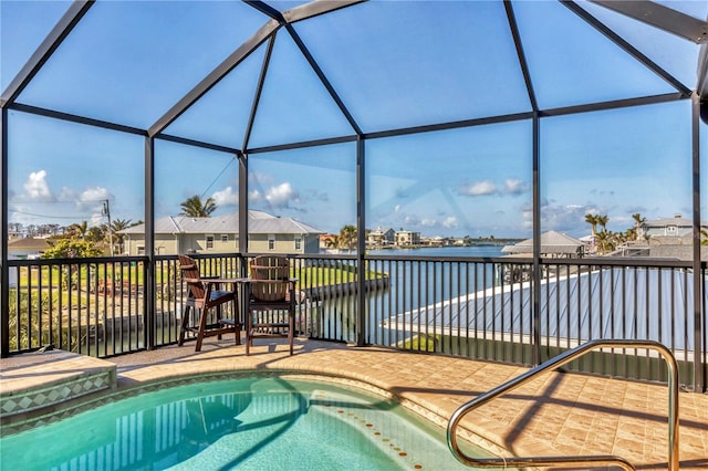 pool with glass enclosure, a patio area, and a water view