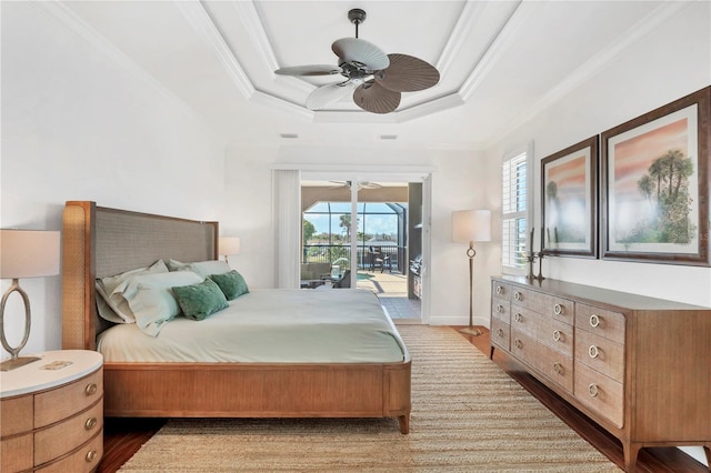 bedroom with crown molding, wood finished floors, a raised ceiling, and access to exterior