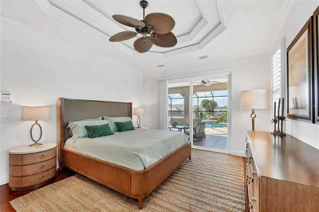 bedroom with a raised ceiling, wood finished floors, access to exterior, ornamental molding, and baseboards