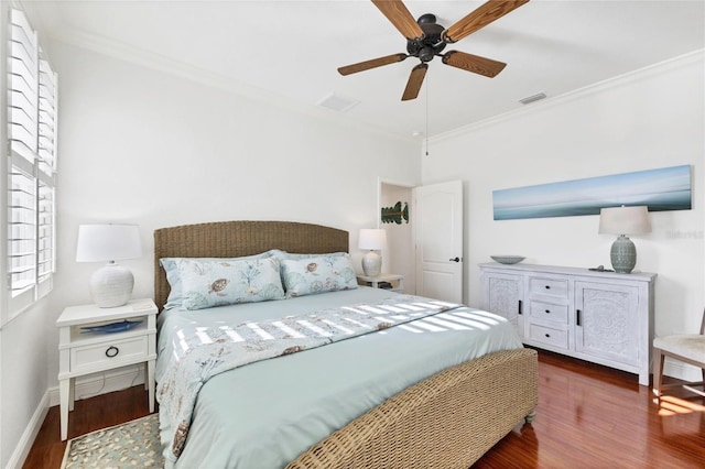 bedroom featuring wood finished floors, visible vents, baseboards, and ornamental molding