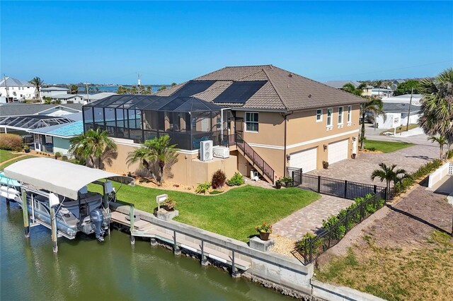 back of property with a water view, fence, a yard, a garage, and stucco siding