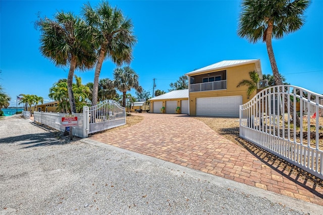 view of front of house with decorative driveway, fence private yard, metal roof, stucco siding, and a standing seam roof