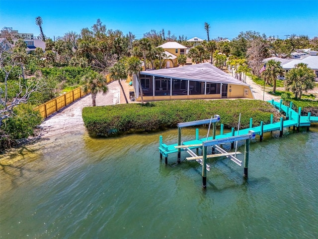dock area with fence, boat lift, and a water view