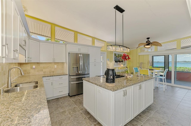 kitchen with white cabinets, a sink, a center island, stainless steel refrigerator with ice dispenser, and ceiling fan