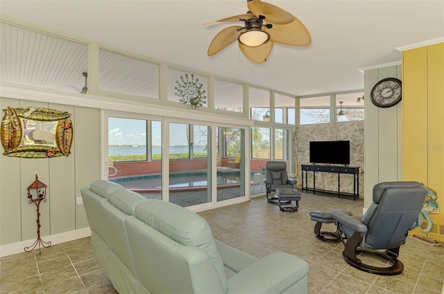 living room with a wealth of natural light, a ceiling fan, tile patterned floors, and baseboards