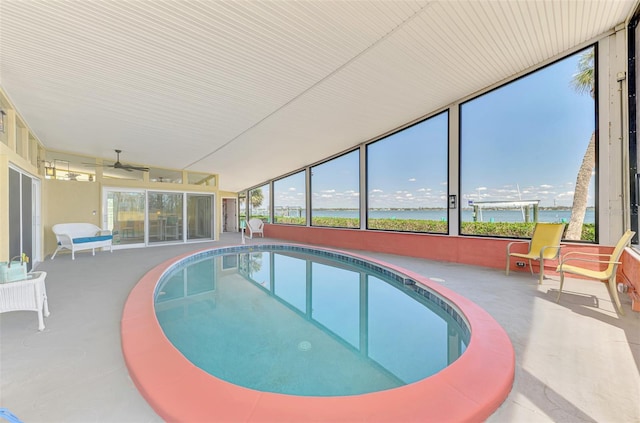pool featuring a patio, a ceiling fan, and a water view