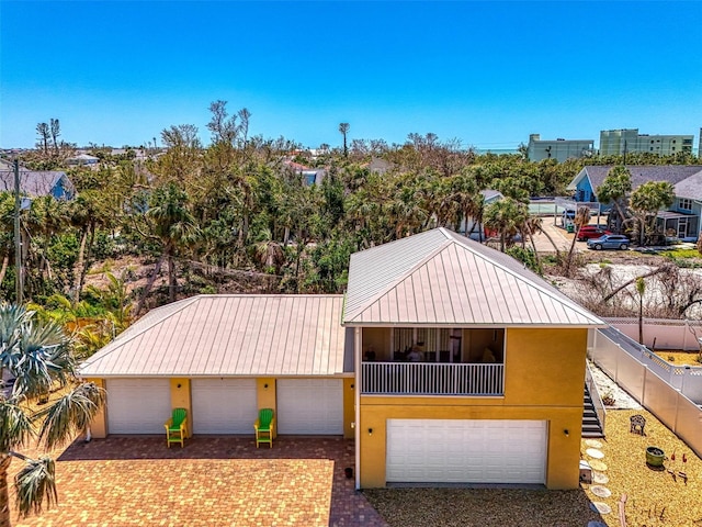 view of front of house featuring stairway, a garage, stucco siding, decorative driveway, and metal roof