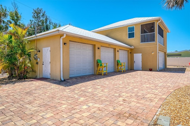 view of front of house featuring stucco siding, fence, decorative driveway, and metal roof