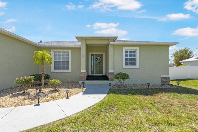 7089 Benson St, Englewood, FL 34224 - view of front facade with stucco siding, fence, and a front yard