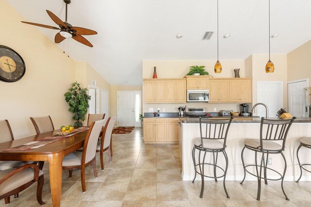 7089 Benson St, Englewood, FL 34224 - kitchen with a ceiling fan, light brown cabinetry, stainless steel appliances, a kitchen bar, and visible vents