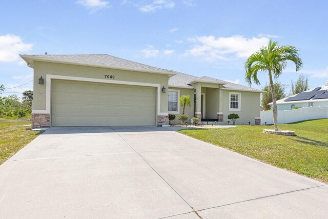 7089 Benson St, Englewood, FL 34224 - view of front facade featuring driveway, stone siding, an attached garage, fence, and a front yard