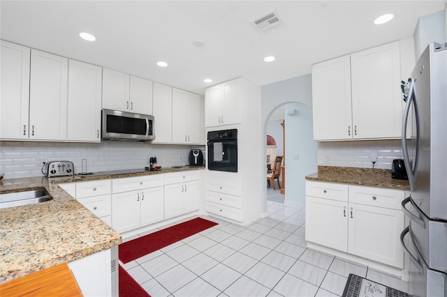 23347 Lehigh Ave, Port Charlotte, FL 33954 - kitchen with stainless steel appliances, backsplash, visible vents, arched walkways, and light stone countertops