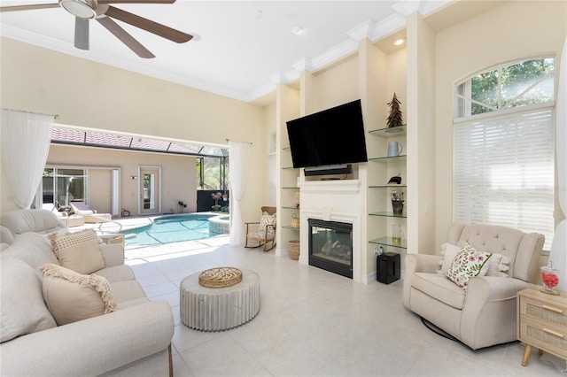 26 Saint Croix Way, Englewood, FL 34223 - living area featuring a ceiling fan, a glass covered fireplace, built in shelves, and ornamental molding