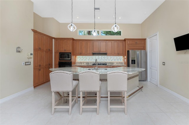 26 Saint Croix Way, Englewood, FL 34223 - kitchen with brown cabinets, a center island with sink, backsplash, a high ceiling, and appliances with stainless steel finishes