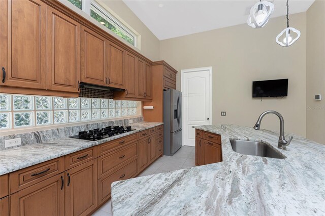 26 Saint Croix Way, Englewood, FL 34223 - kitchen with brown cabinets, stainless steel fridge, black gas cooktop, and a sink