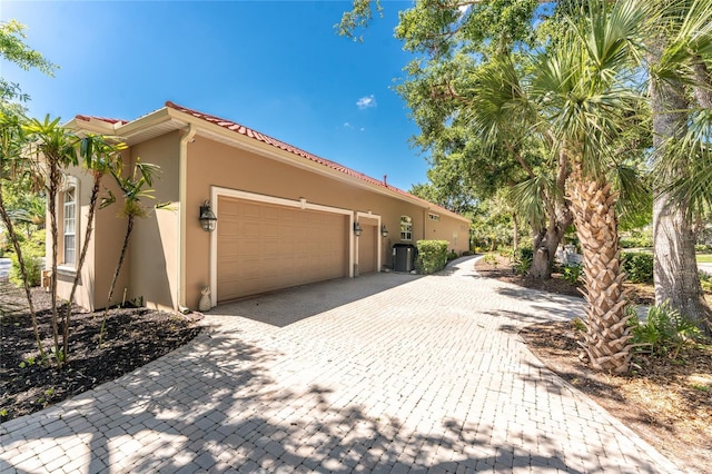 26 Saint Croix Way, Englewood, FL 34223 - view of home's exterior with decorative driveway, a tiled roof, an attached garage, cooling unit, and stucco siding