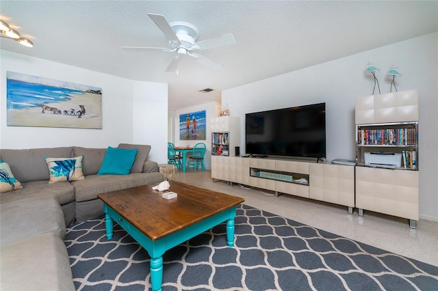 living area featuring a textured ceiling, speckled floor, a ceiling fan, and visible vents